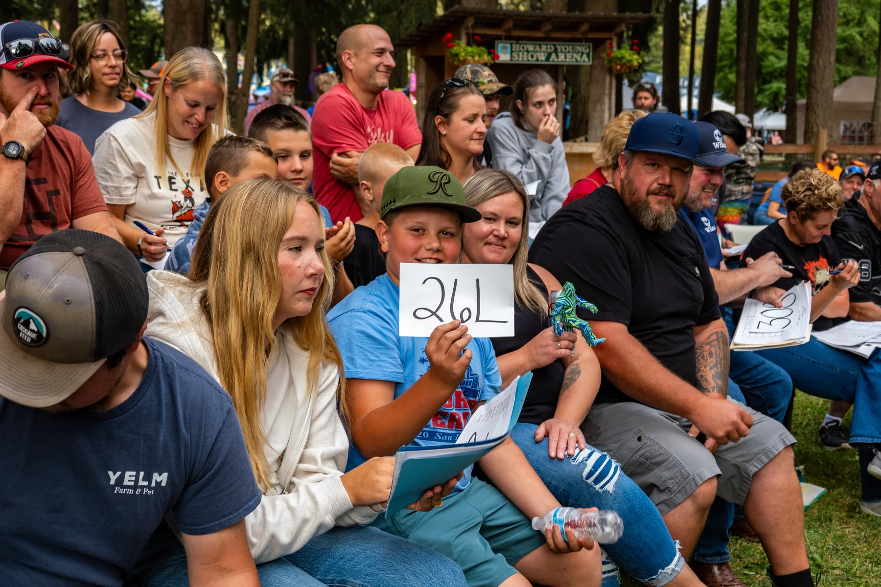 A group of sale attendees watches the auction, with a bidder number held up in the foreground.